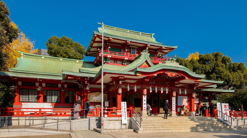 Um templo japonês tradicional com telhado de vários níveis e detalhes em vermelho e verde.