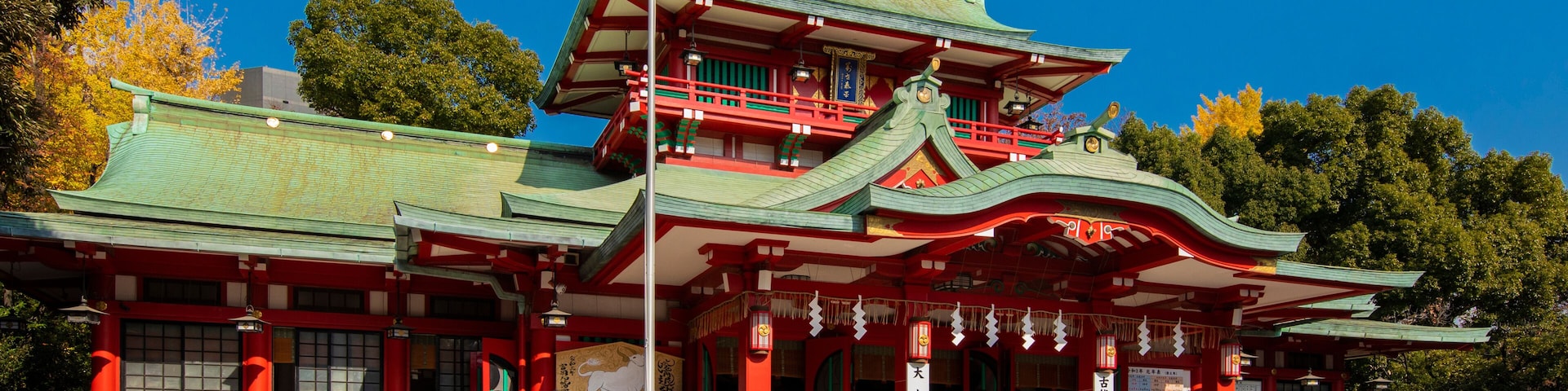 Un temple japonais traditionnel, doté d’un toit à plusieurs niveaux et orné de touches de rouge et de vert.