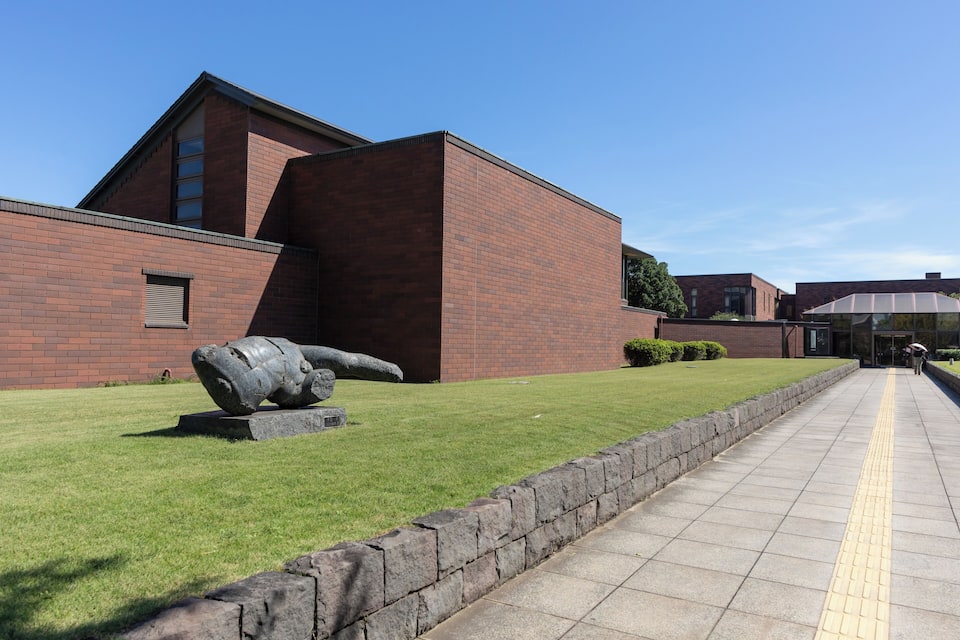 A building with a brick facade and a large sculpture in front.