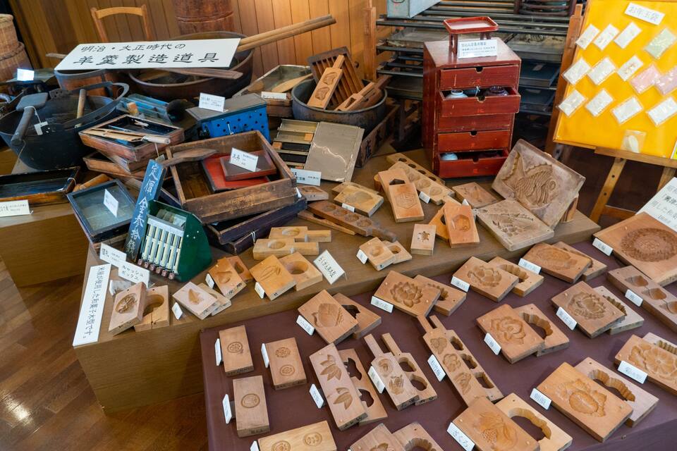 A display of traditional Japanese woodworking tools and carved wooden pieces.