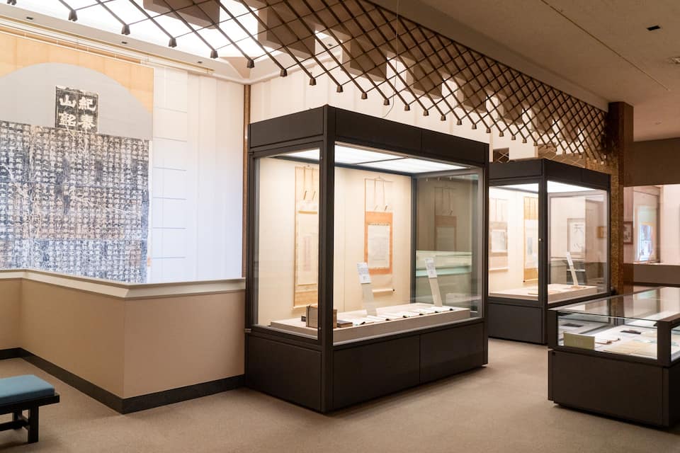 Interno di un museo con vetrine e mostre esposte alle pareti.