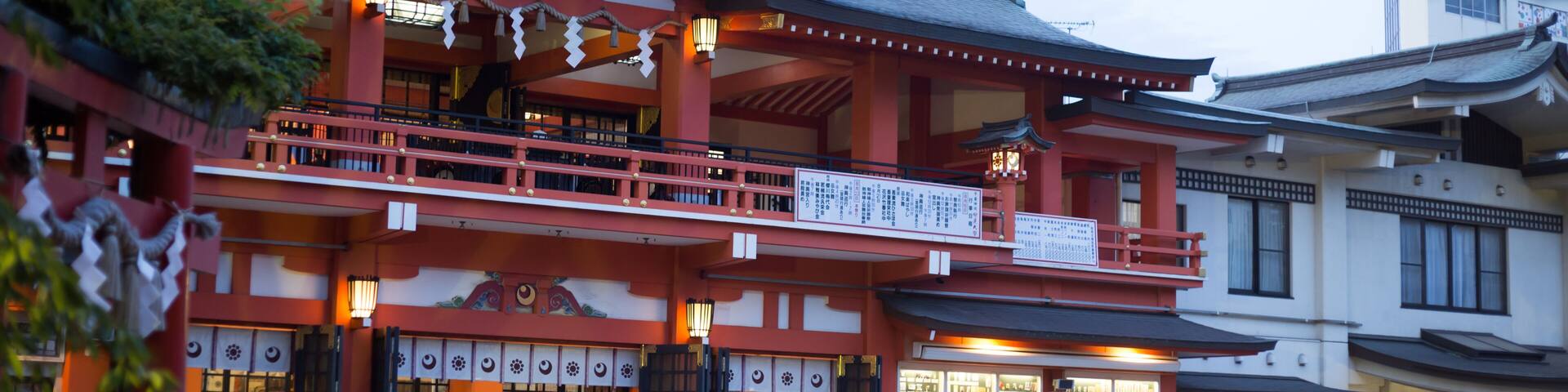 A traditional Japanese building with a red and white facade, a balcony, and a signboard.
