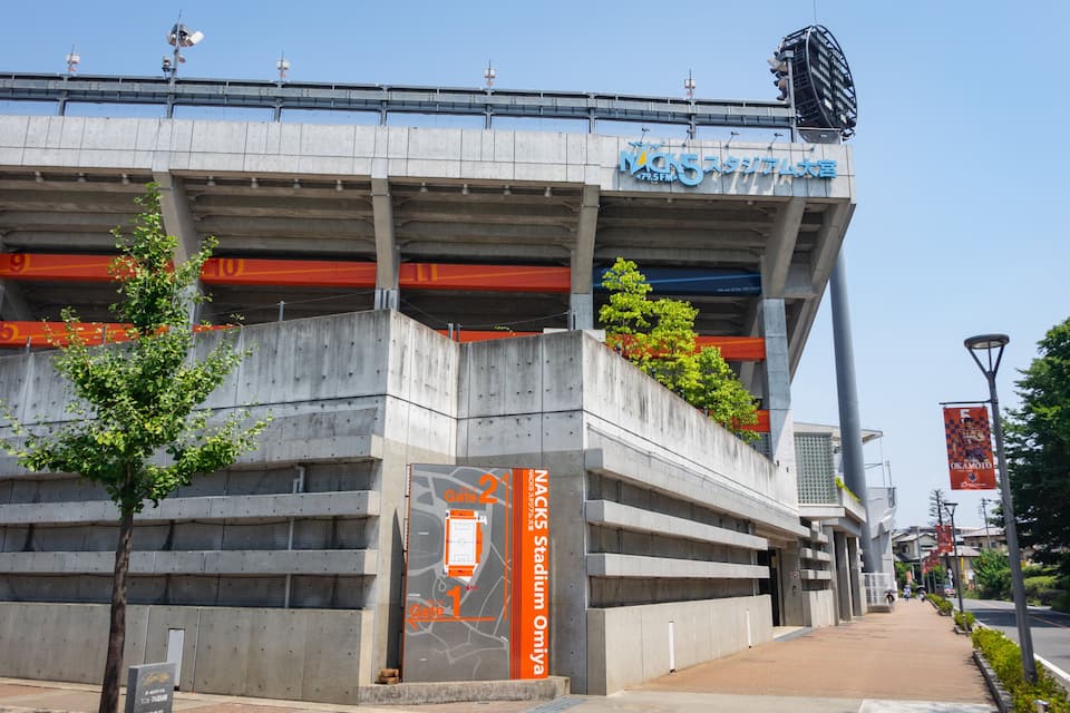 A modern sports stadium with multiple levels and a prominent entrance gate.