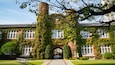 A historic building with ivy-covered brick walls and a central archway.