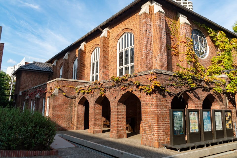A historic brick building with arched windows and ivy climbing up the walls.