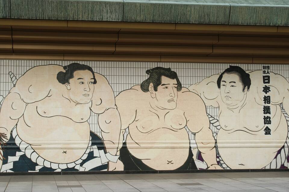 A mural of sumo wrestlers on a tiled wall.