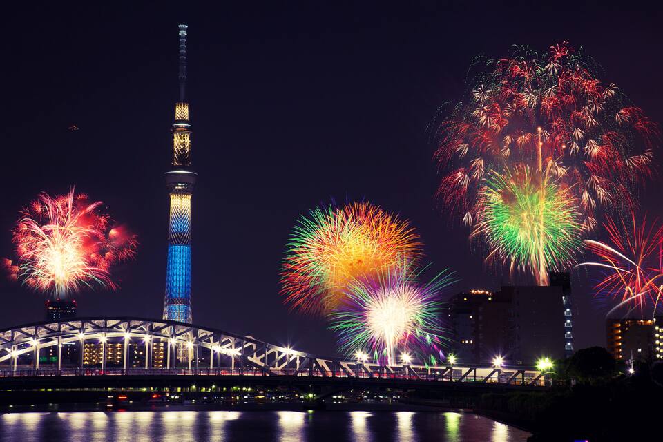 A bridge, a tower, and fireworks over water.