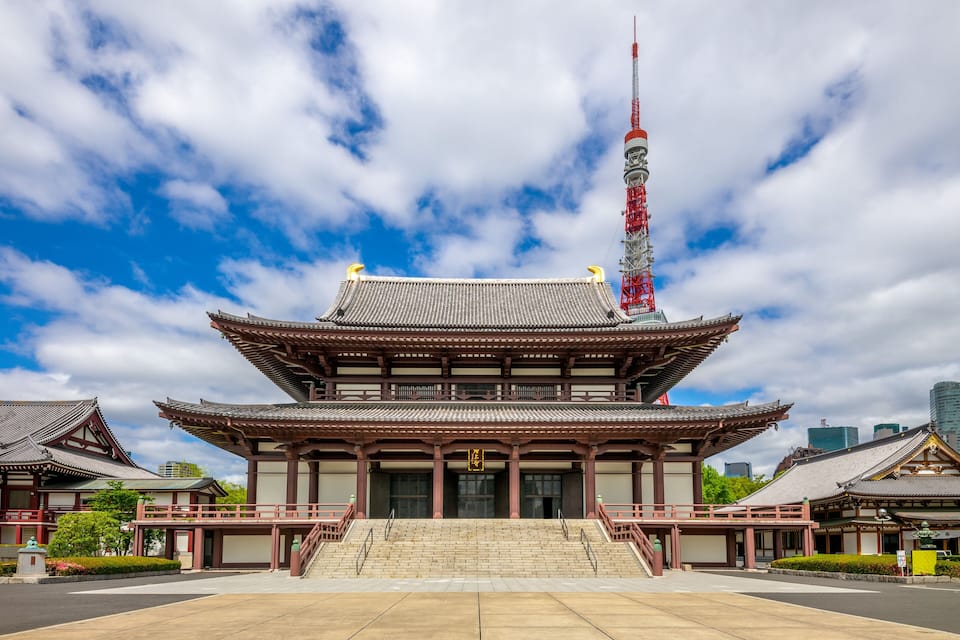 A traditional Japanese temple with a prominent red tower and a large staircase leading to the entrance.
