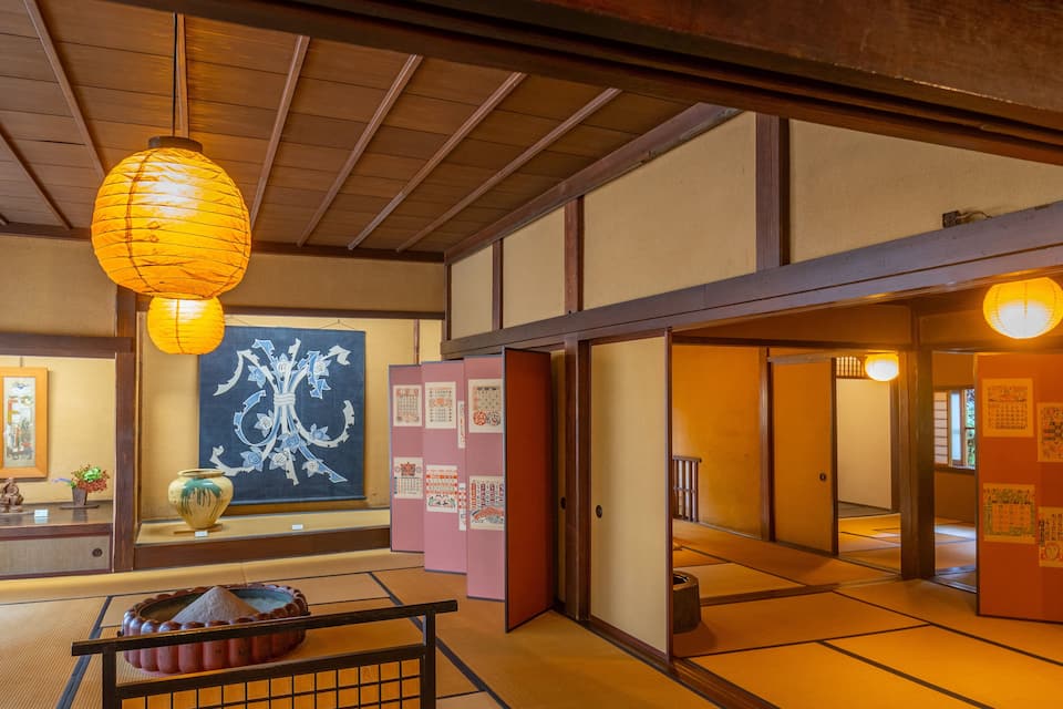 A traditional Japanese interior with tatami flooring, shoji screens, and hanging paper lanterns.
