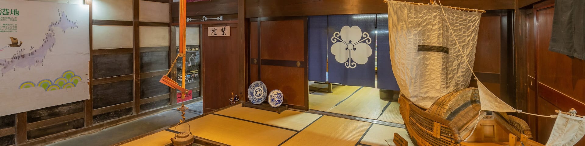 A traditional Japanese room with tatami flooring, a wooden boat, and a hanging lantern.