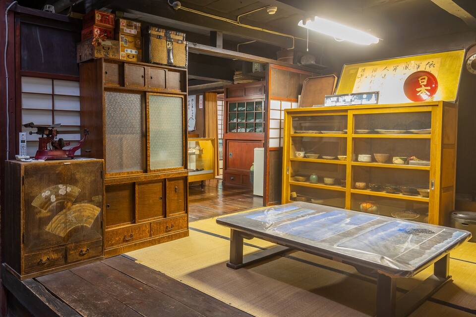 Una habitación japonesa tradicional con mobiliario de madera, una mesa con superficie de vidrio y un reloj en la pared.