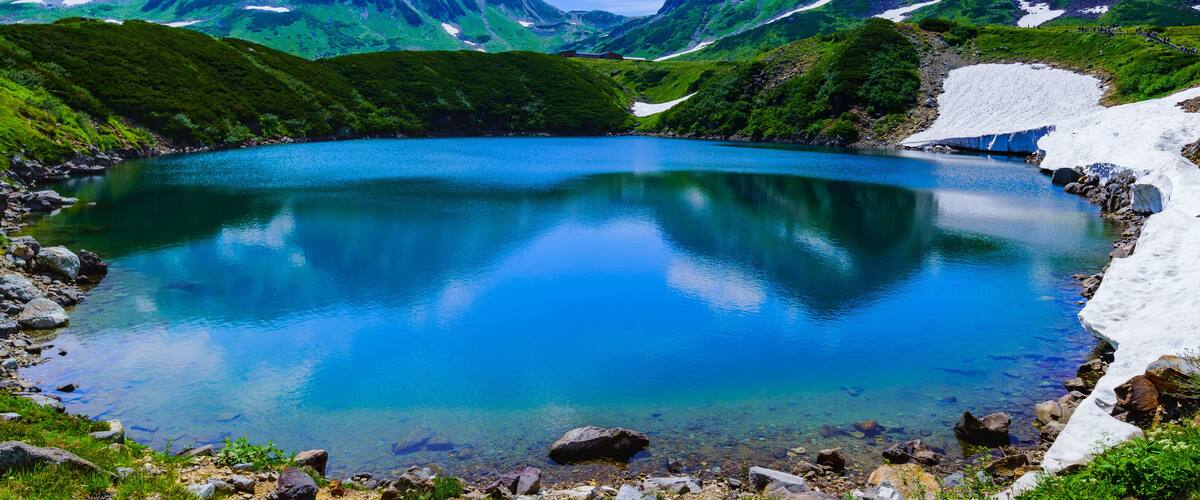 A mountain lake surrounded by snow-capped peaks and lush greenery.