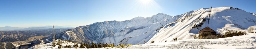 Hakuba mountain range on a clear sunny day. The very steep mountain area is between two ski resorts, Happo-One and Goryu. A natural flat area between the ranges is inhabited by the local villagers.; S