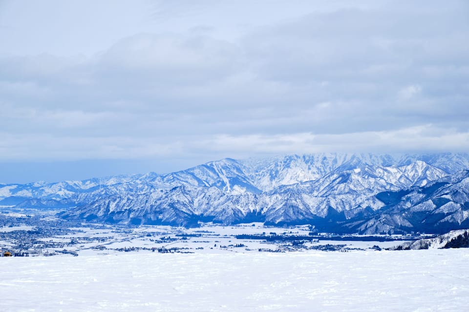 A snow-covered mountain range with a town in the foreground.