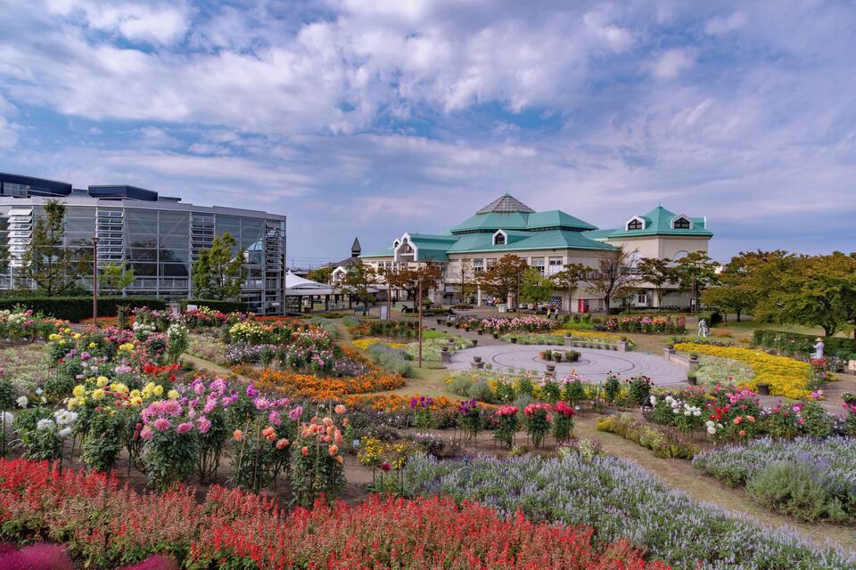 A large building with a green roof and a garden with colorful flowers.