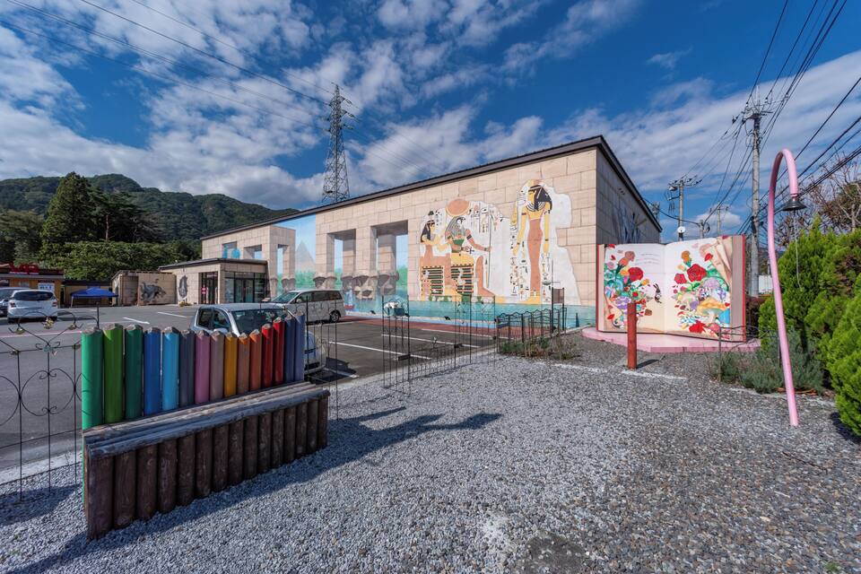 A building with colorful murals, a parking lot, and a mountainous landscape in the background.