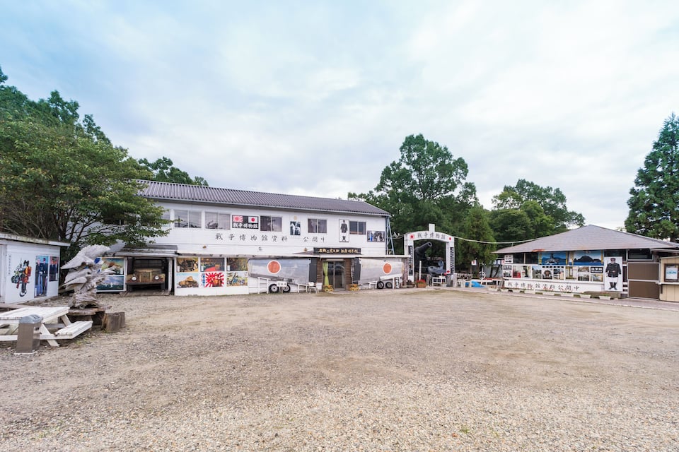 Edifício com sinalização japonesa, rodeado por cascalho e árvores.