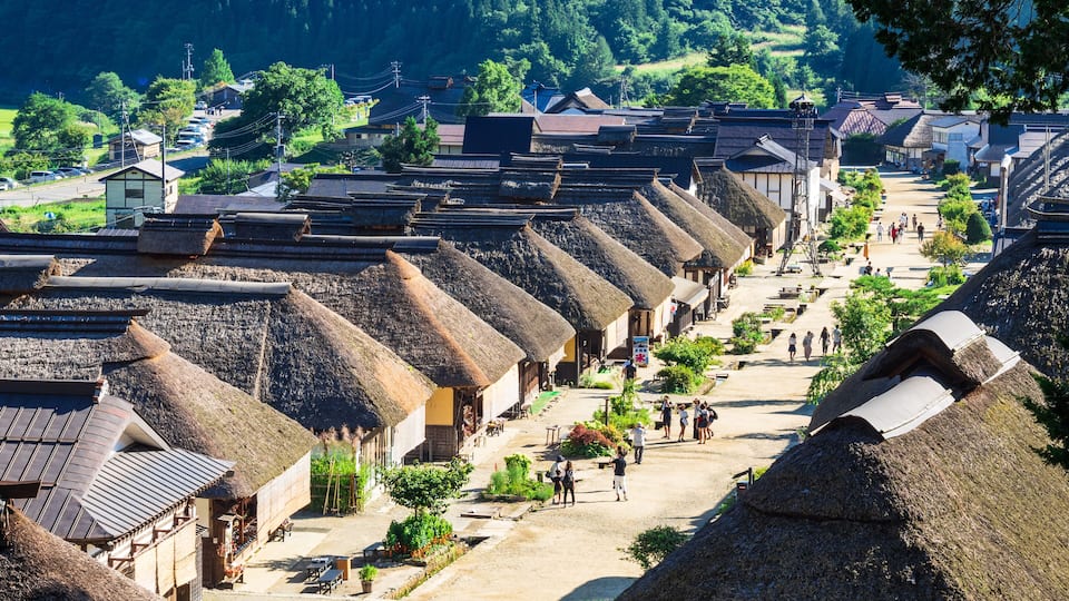 A traditional village with thatched-roof houses and a dirt road.