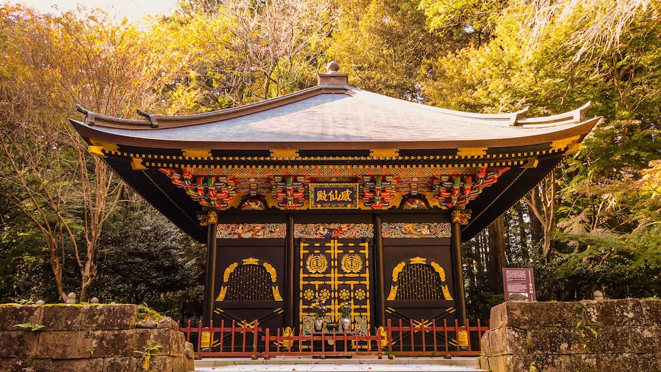Un templo japonés tradicional con decoraciones ornamentales, rodeado de abundante vegetación.