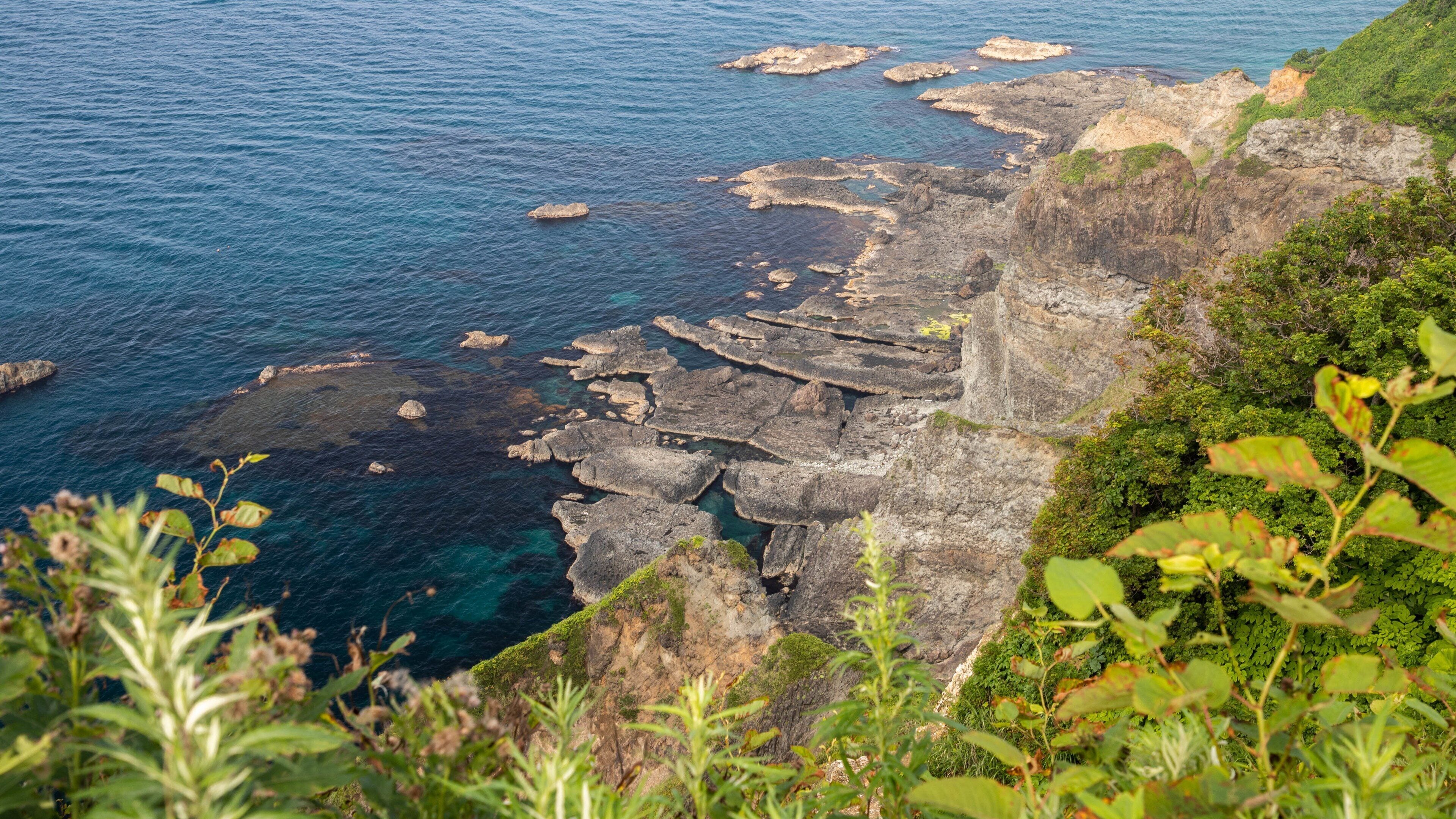Paisagem costeira com falésias rochosas e mar azul límpido.