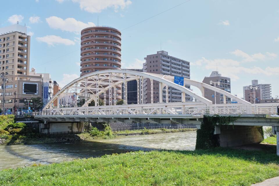 Uma ponte sobre um rio, com edifícios modernos ao fundo.