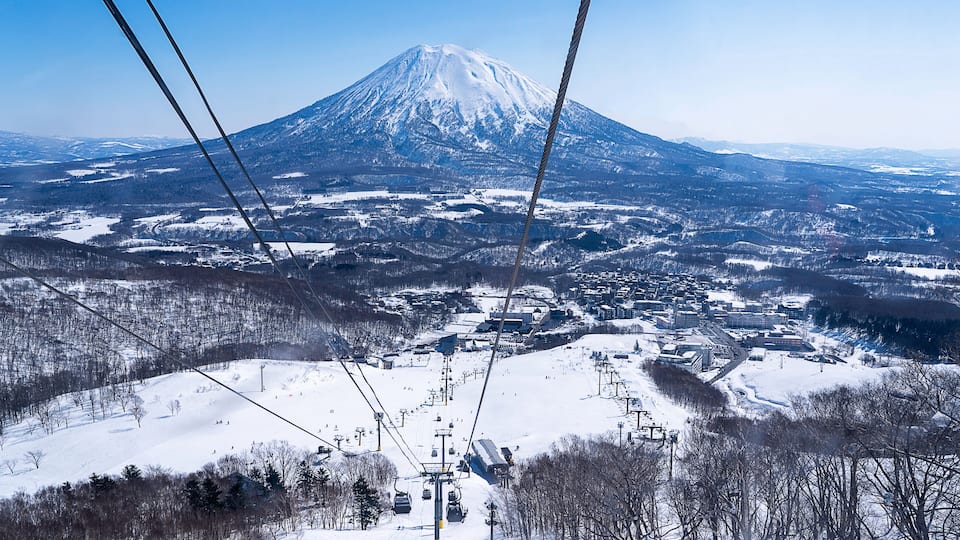 A snow-covered mountain with a ski lift in the foreground.