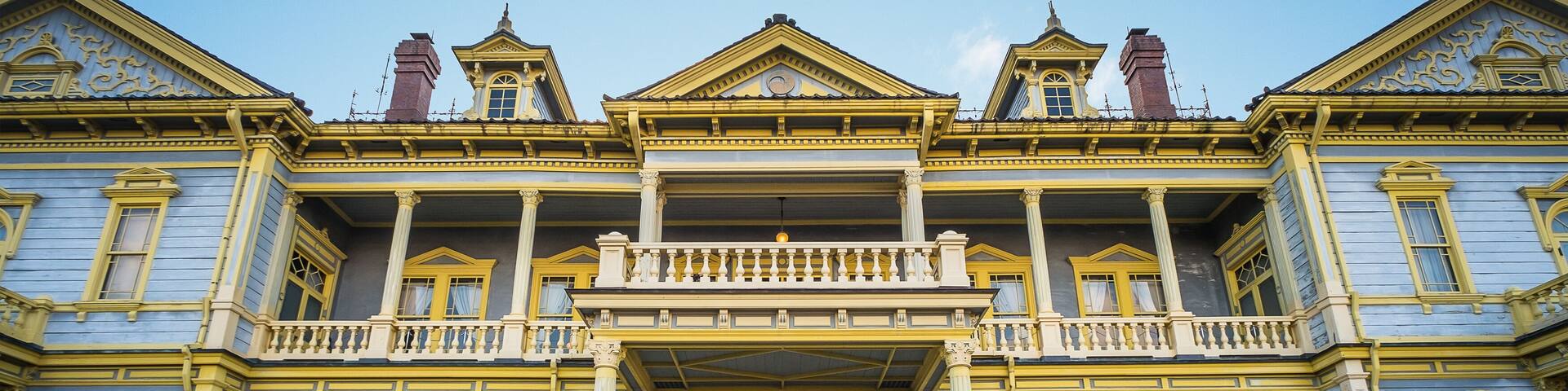 Un edificio grande y ornamentado con detalles en amarillo y azul, un balcón central y una fachada simétrica.