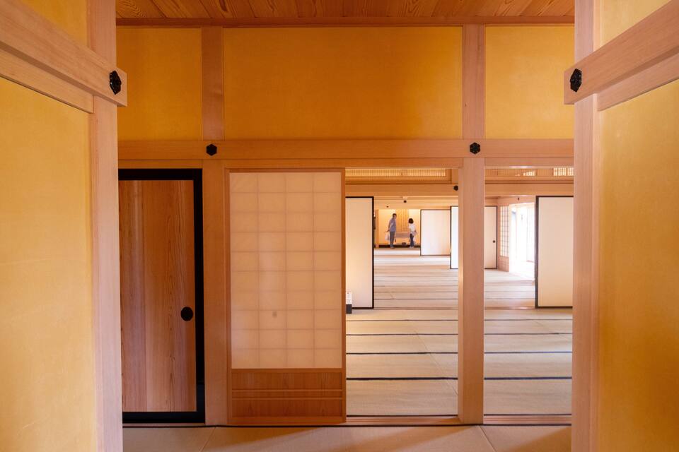 A traditional Japanese interior with wooden beams, tatami flooring, and sliding doors.