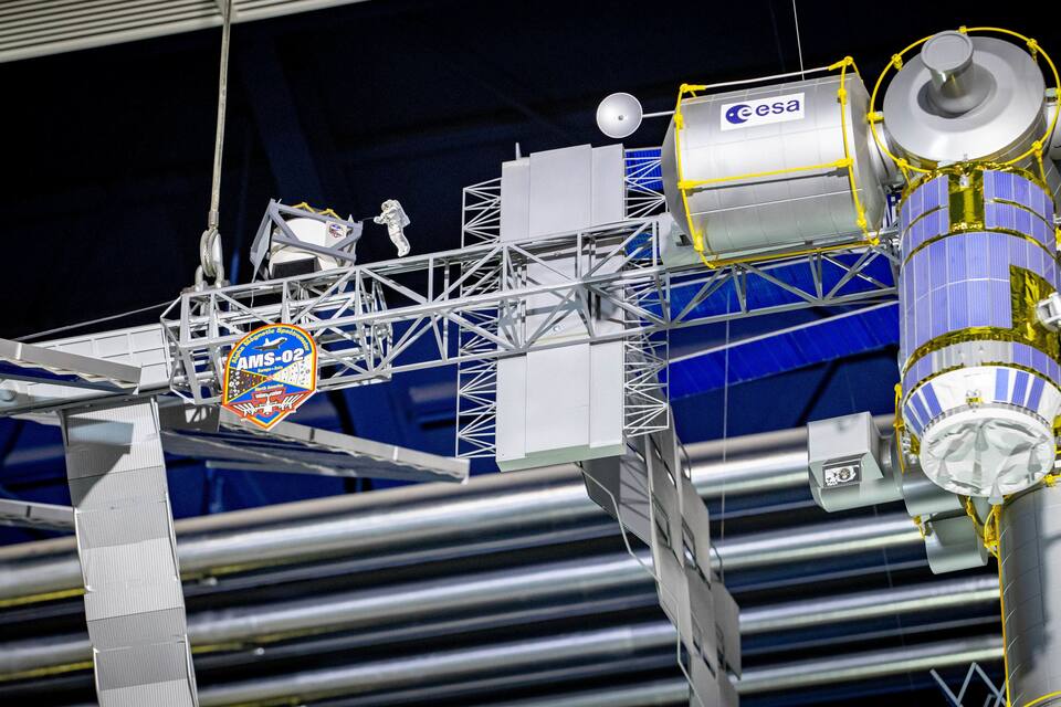 Uma montagem de satélite com um logotipo que diz "AMS-02" e "ESA".