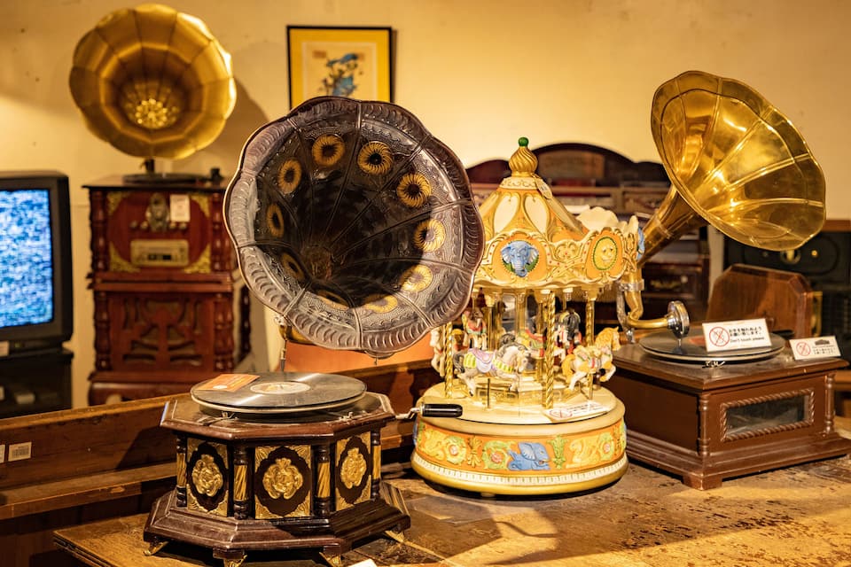 A collection of antique gramophones and record players on a wooden table.
