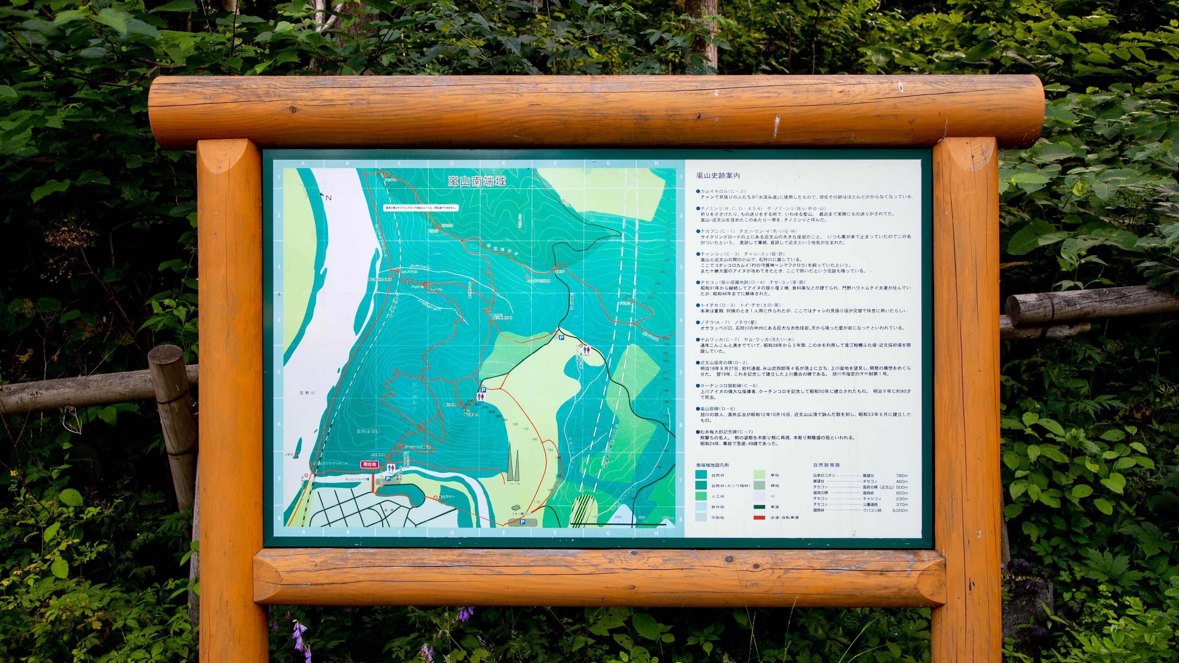 Une carte topographique encadrée en bois, entourée de verdure.