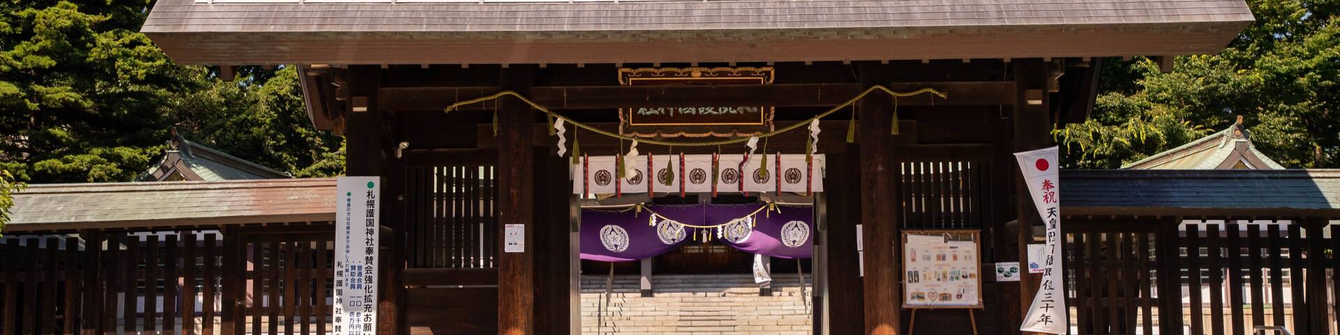 A traditional Japanese gate with wooden pillars and a tiled roof.