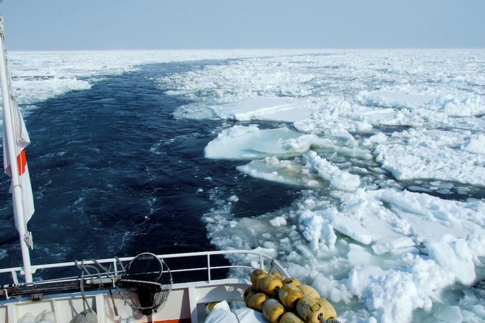 A ship navigating through icy waters with floating ice chunks.