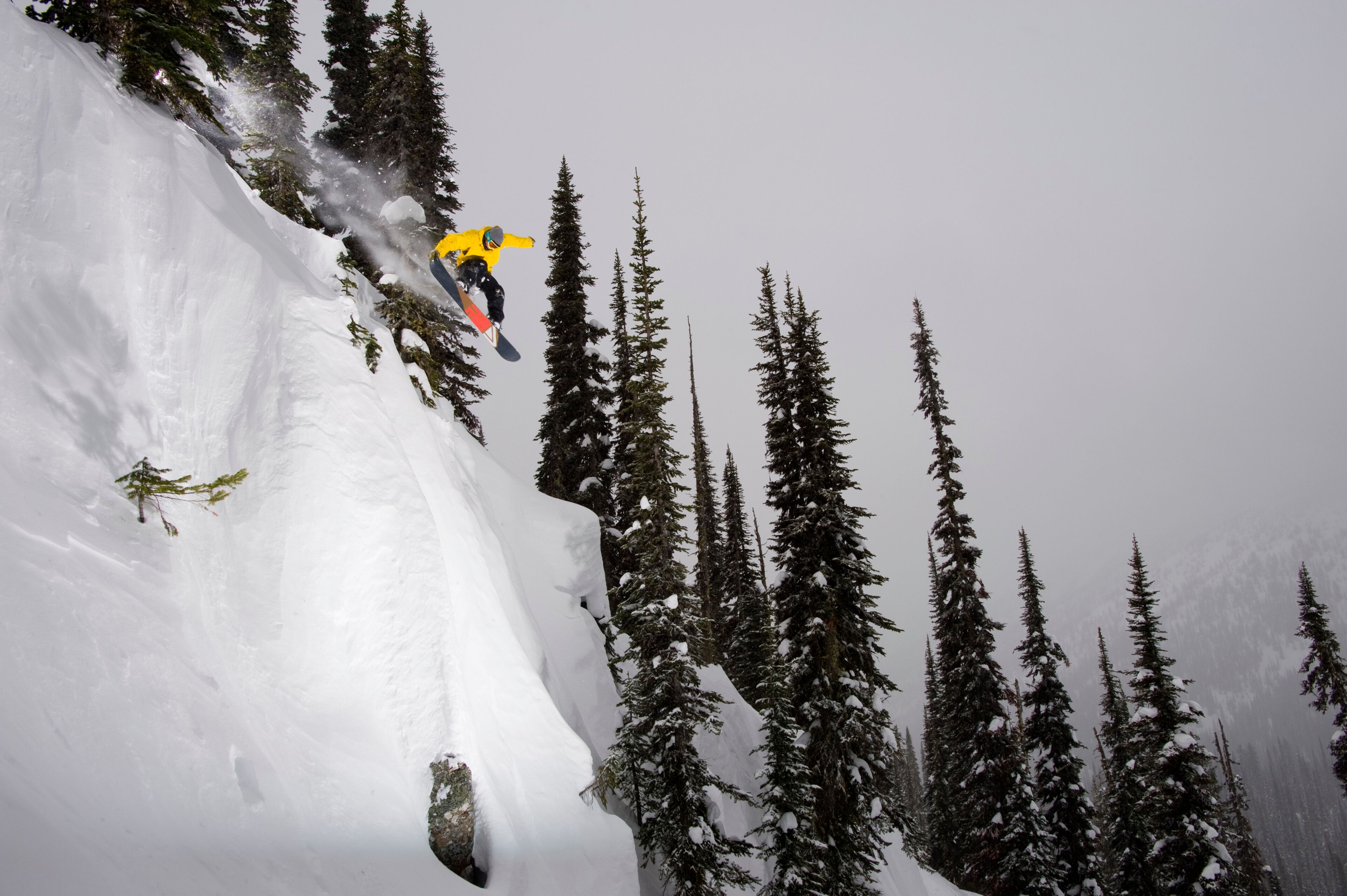 Man hitting a cliff on his snowboard at Baldface Lodge near the Selkirk Mountains in B.C. Canada.