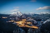 A snow-covered mountain range with a town illuminated by lights in the valley below.