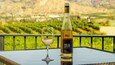 A bottle of wine and a glass on a table with a vineyard in the background.