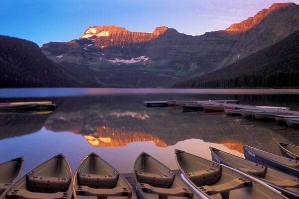 Row boats moored at pier on Cameron Lake, alpenglow on mountains