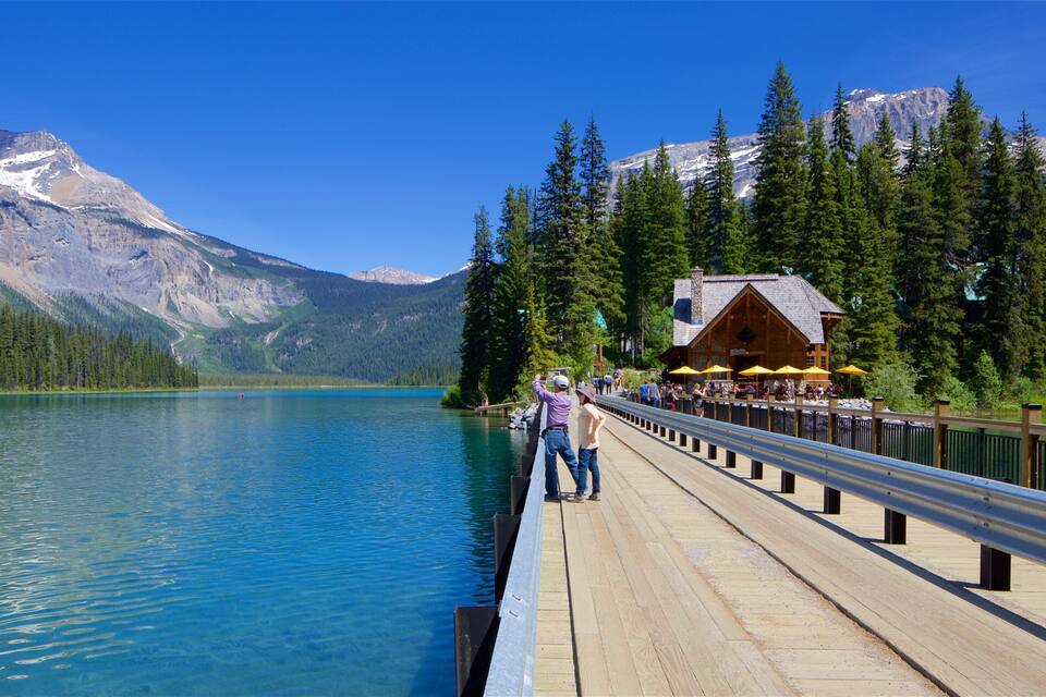 A wooden pier extending over a calm lake with a mountain backdrop.