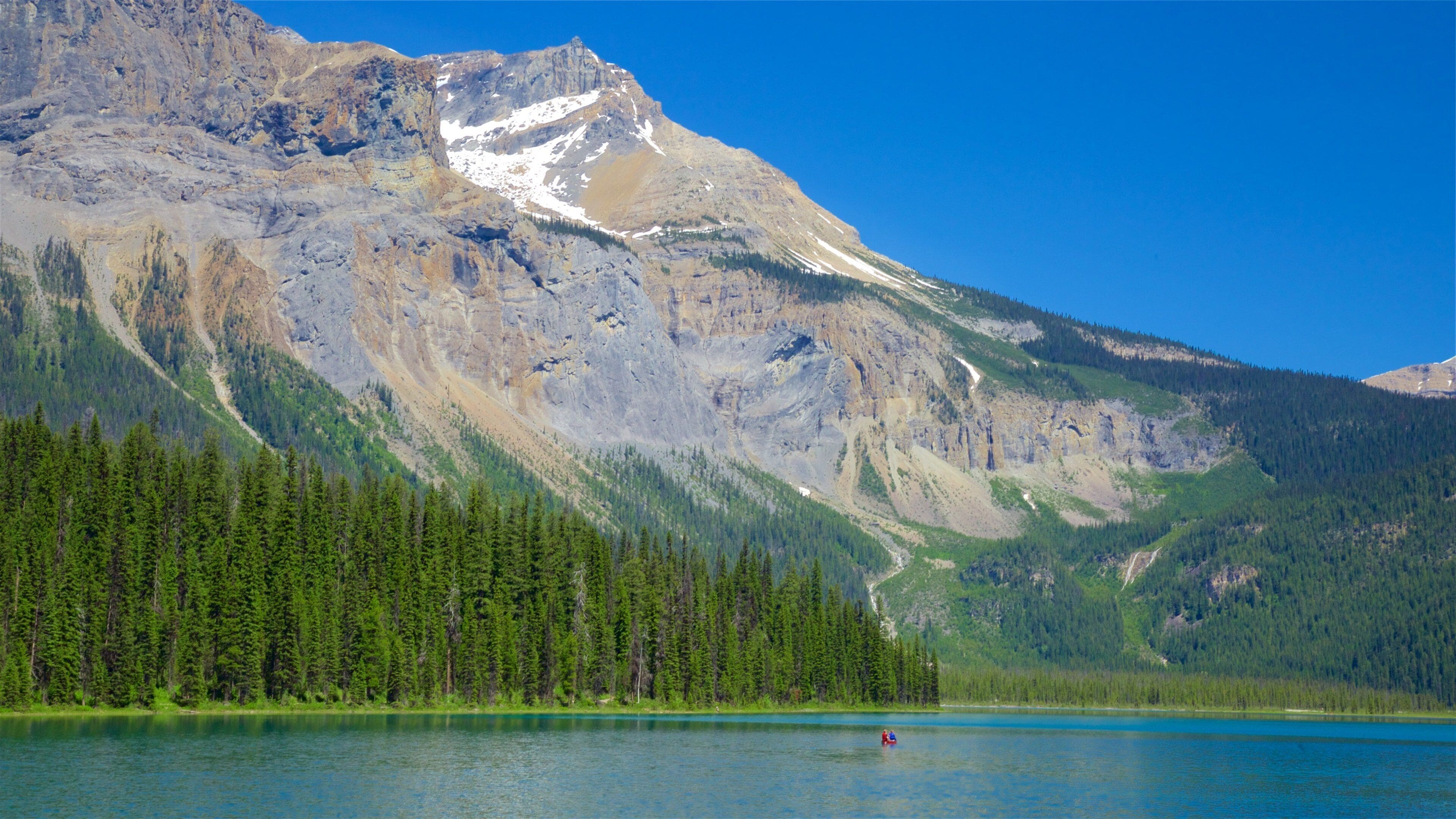 A mountain range with a lake and dense forest.