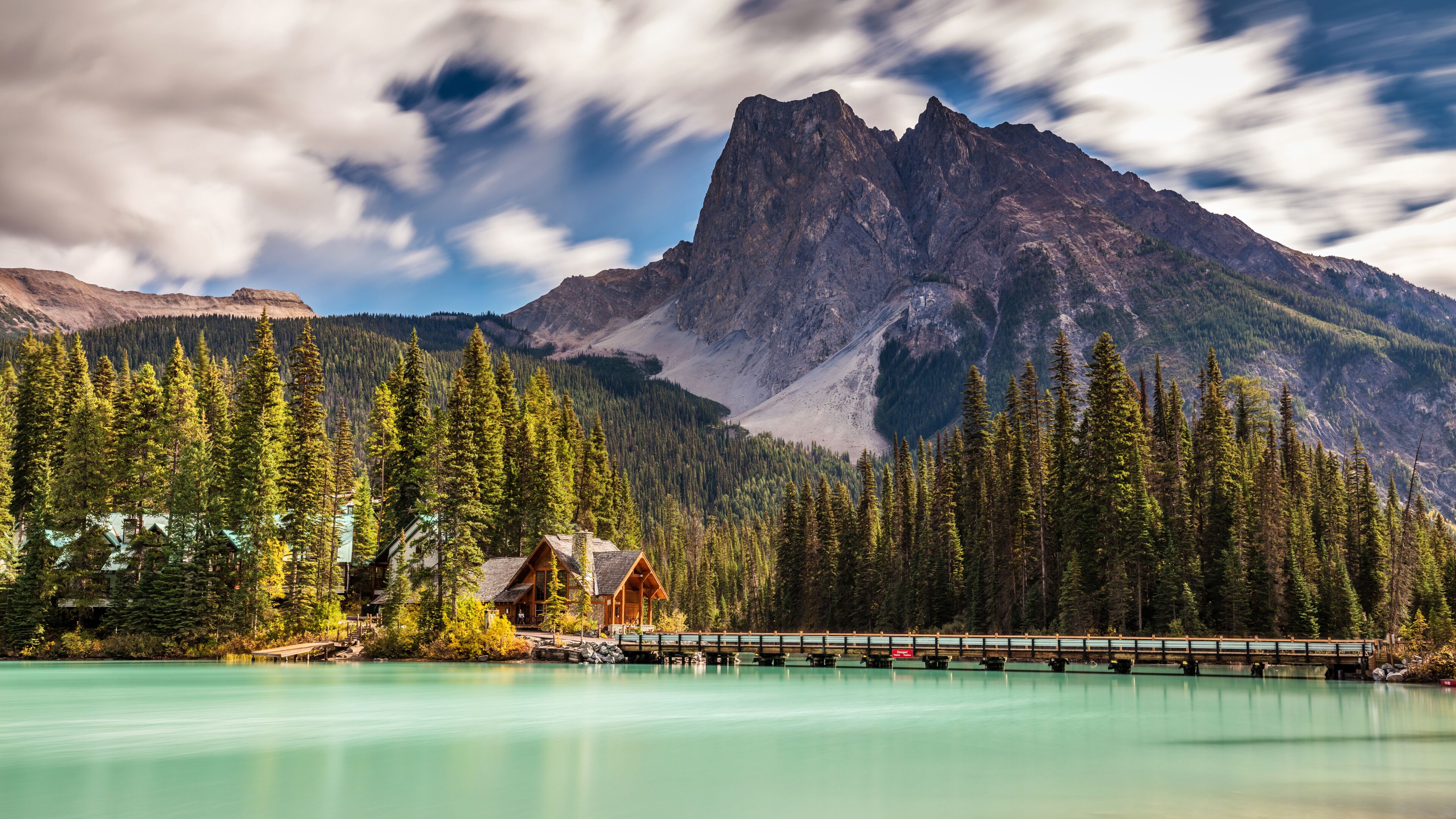 A mountain range, a lake, and a wooden cabin.