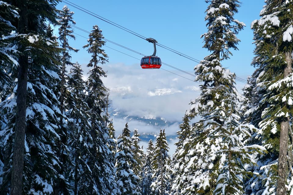 A red cable car moving through a snowy forest.