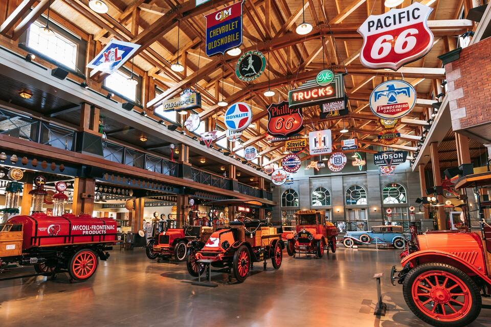 A vintage-themed indoor exhibit with antique vehicles and hanging signs.