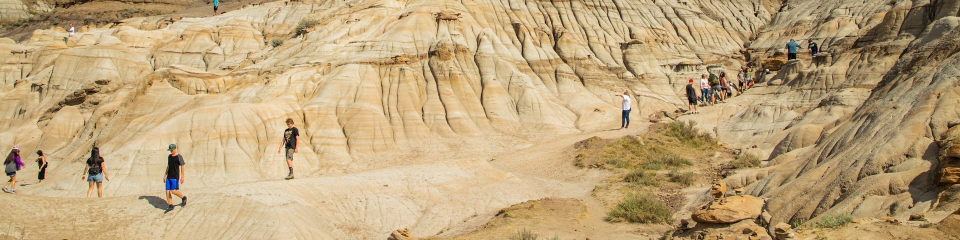 Drumheller Hoodoos featuring a gorge or canyon and mountains as well as a small group of people
