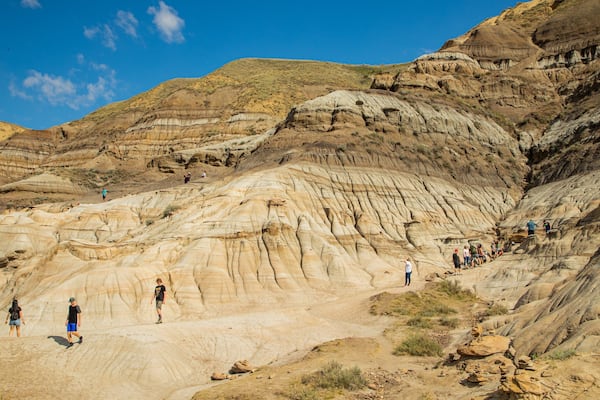 Drumheller Hoodoos featuring a gorge or canyon and mountains as well as a small group of people