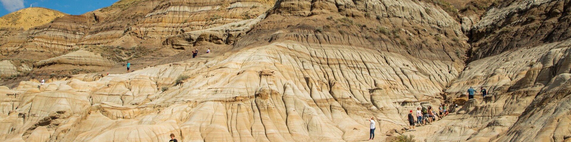 Drumheller Hoodoos featuring a gorge or canyon and mountains as well as a small group of people