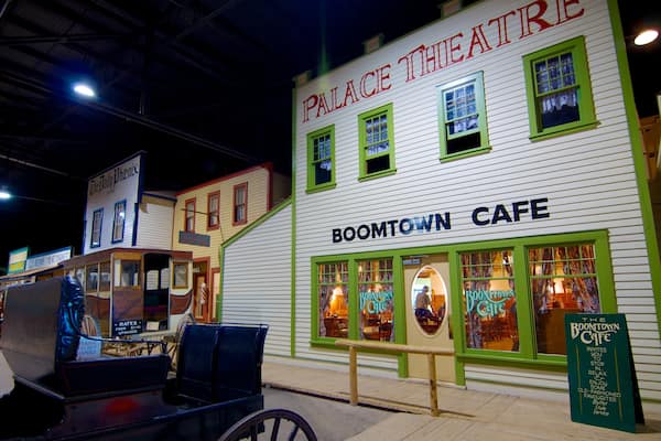 Um edifício com as placas "Palace Theatre" e "Boomtown Cafe", janelas com moldura verde e uma placa.