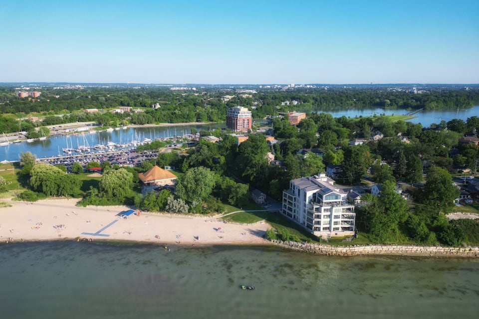 Luftaufnahme einer Küstenstadt mit einer Marina, Strand und umliegender Bepflanzung.