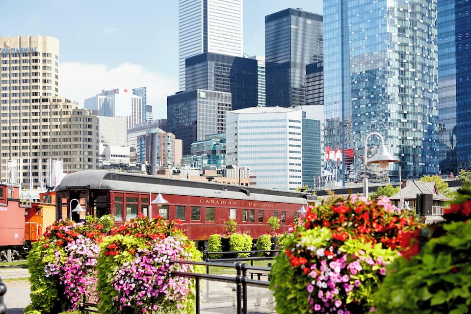 A cityscape with modern skyscrapers, a vintage train, and vibrant flower gardens.