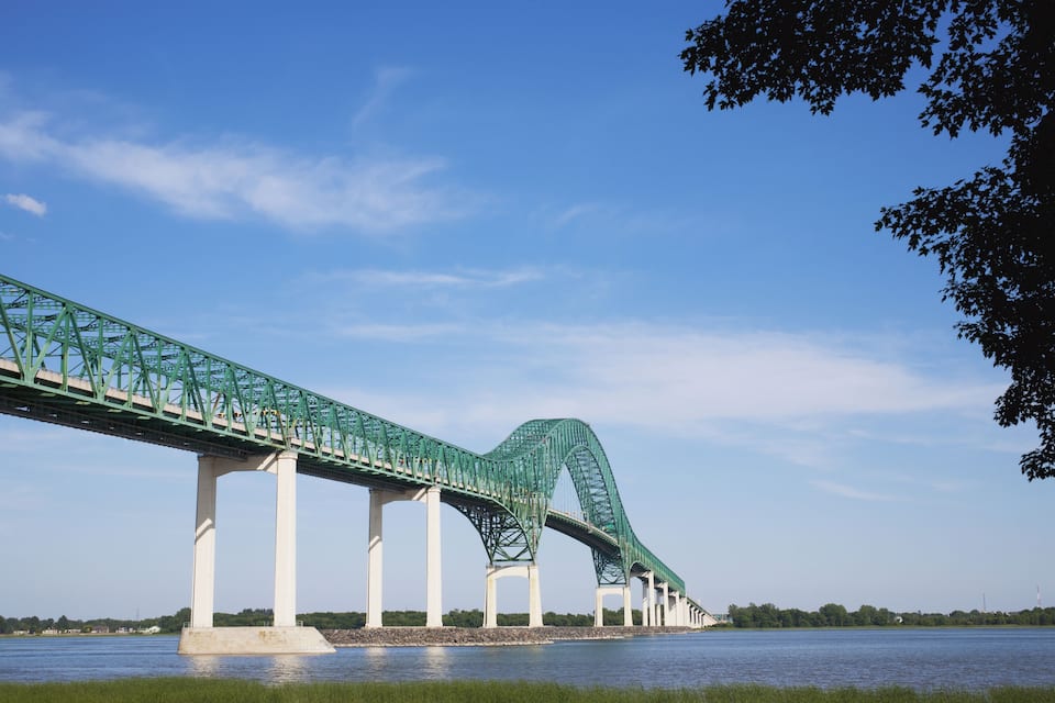 A large green bridge spanning a river with a clear blue sky.