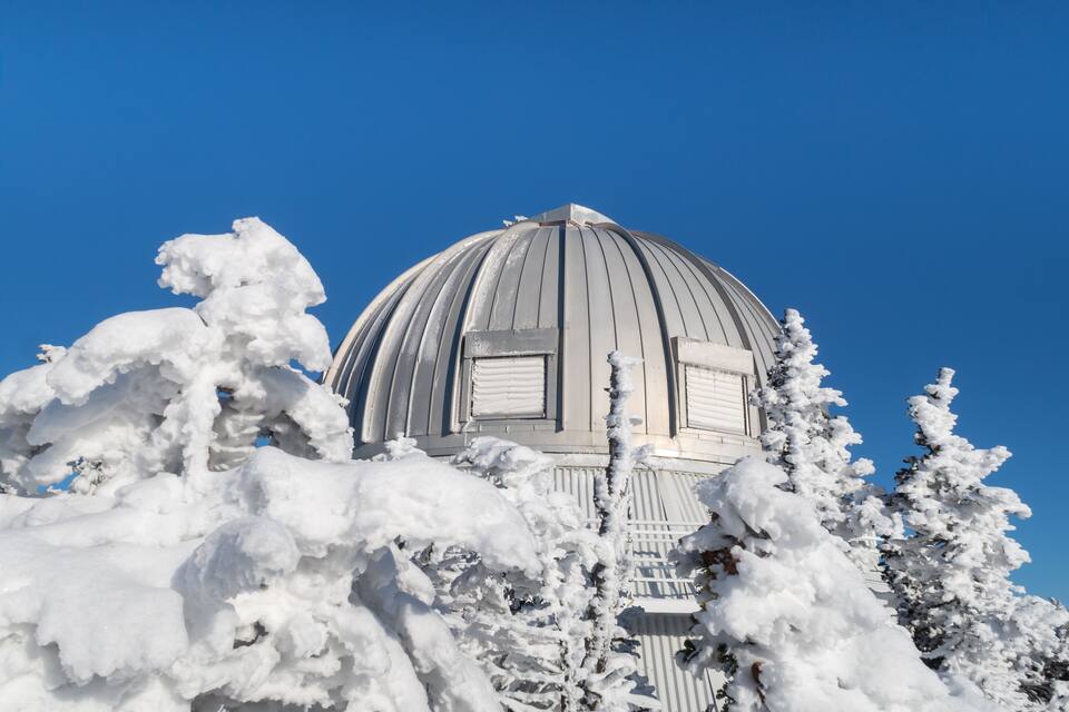 Una estructura en forma de cúpula cubierta de nieve, con un cielo azul despejado al fondo.